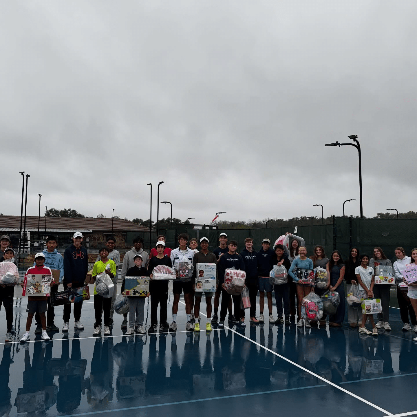 Group of tennis players holding gifts on court